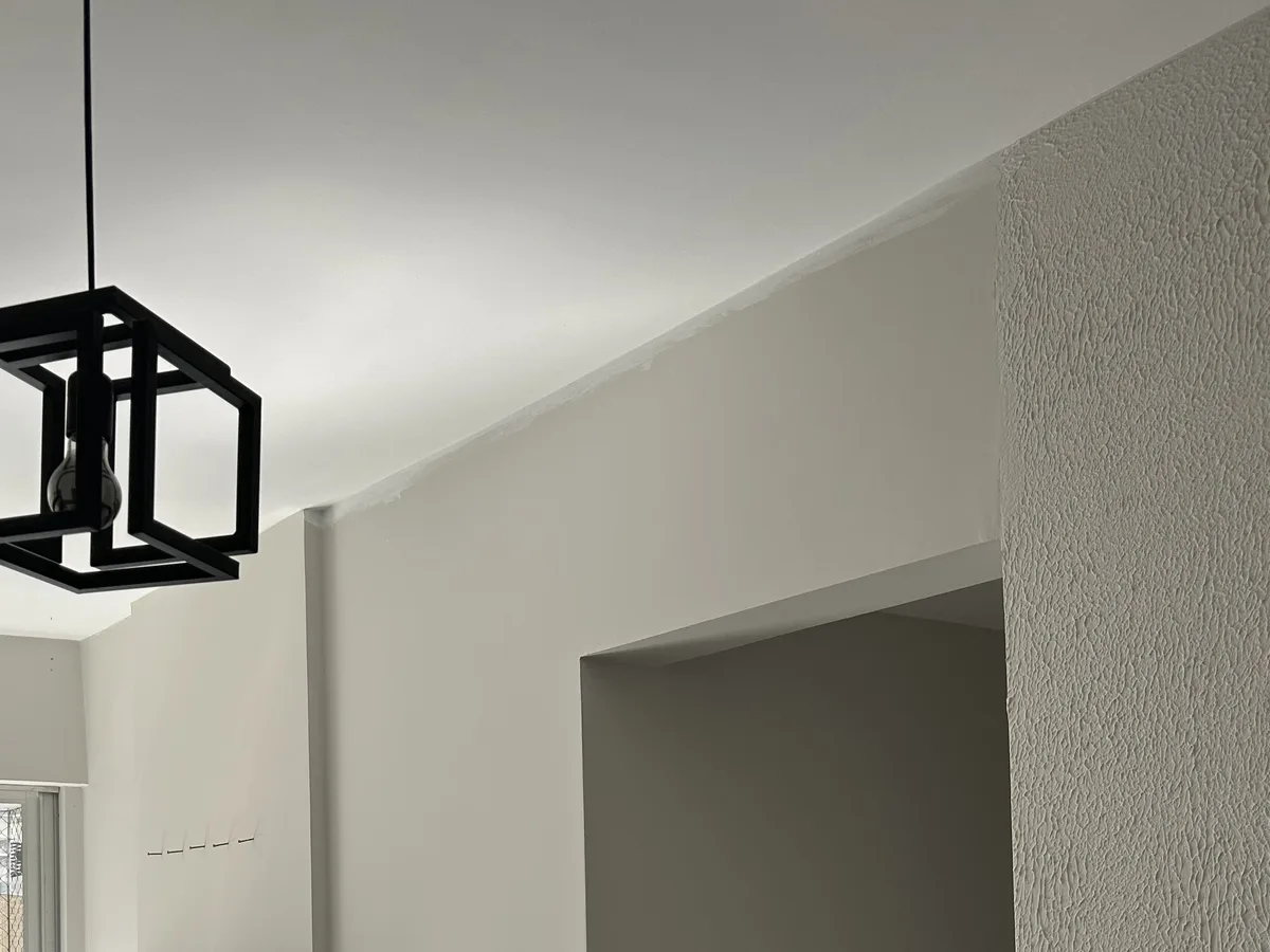 Parede lisa de sala antes da aplicação de papel, com vão de passagem à direita