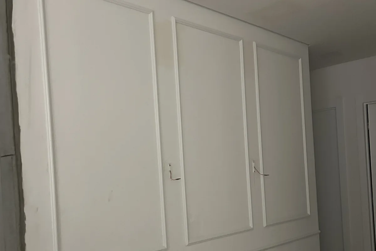 Boiserie aplicada e pintada de branco em uma divisória