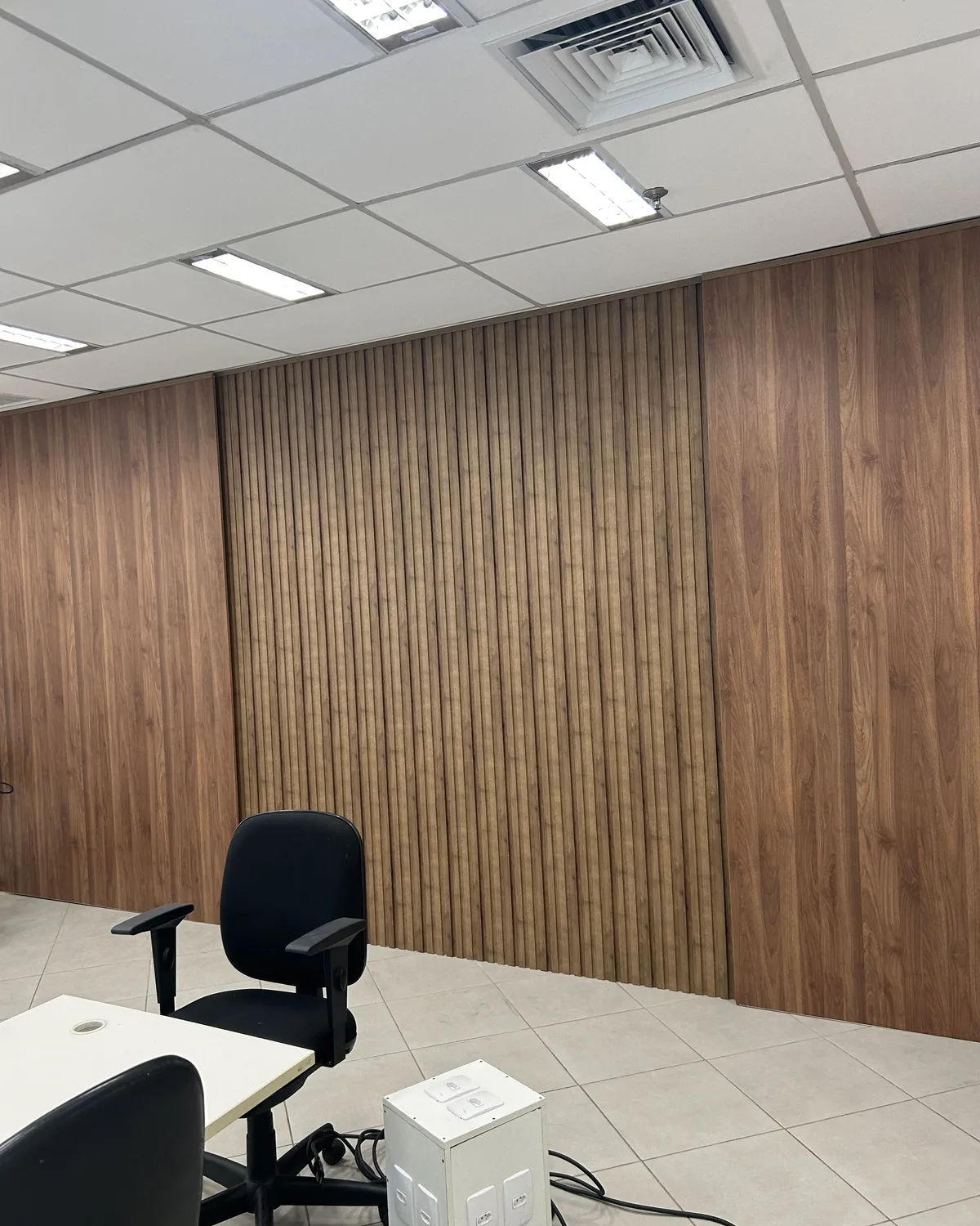 Revestimento da parede do escritório. Forro, iluminação e móveis já fazem parte do ambiente.