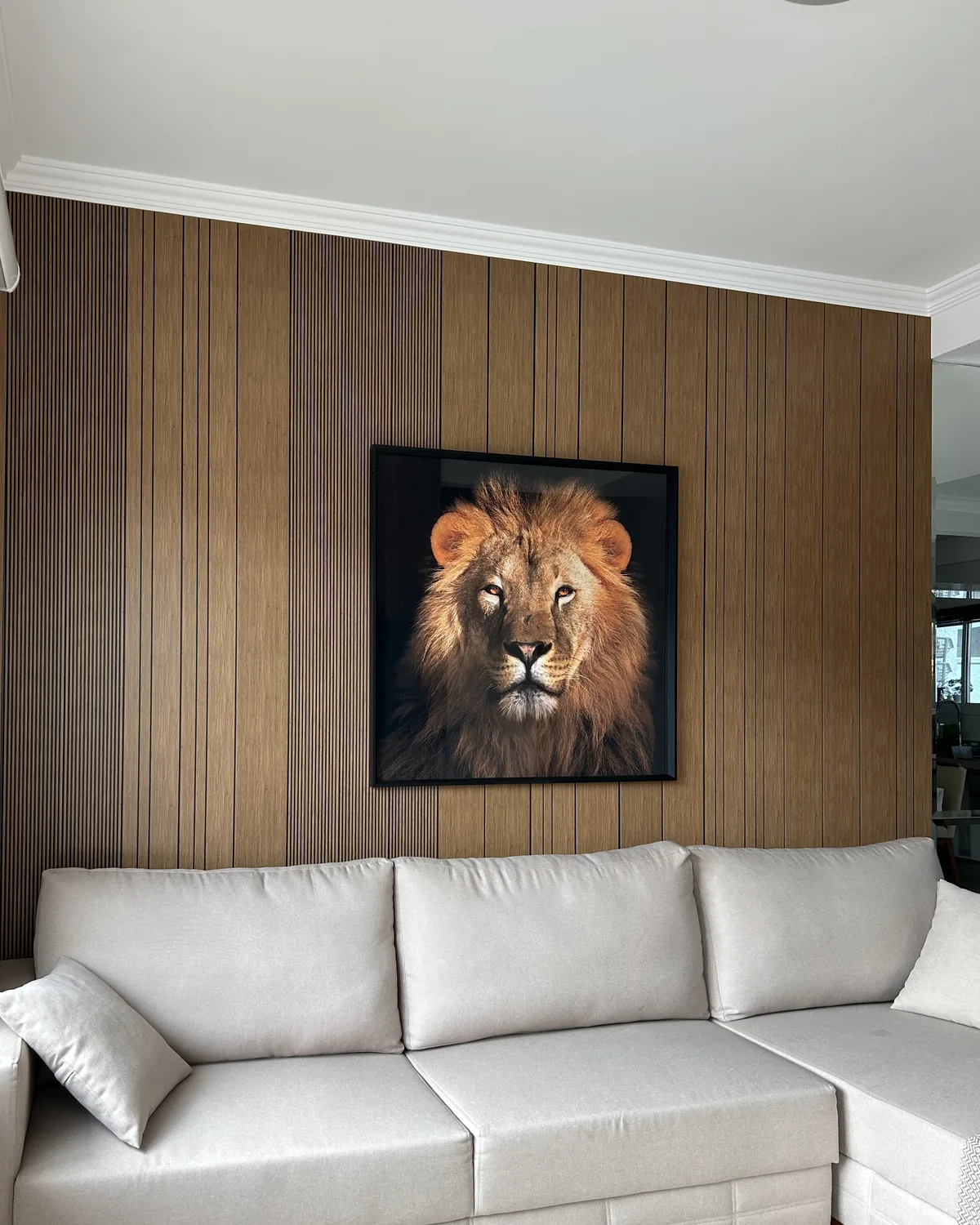 Parede de sala com revestimento de acabamento amadeirado atrás do sofá