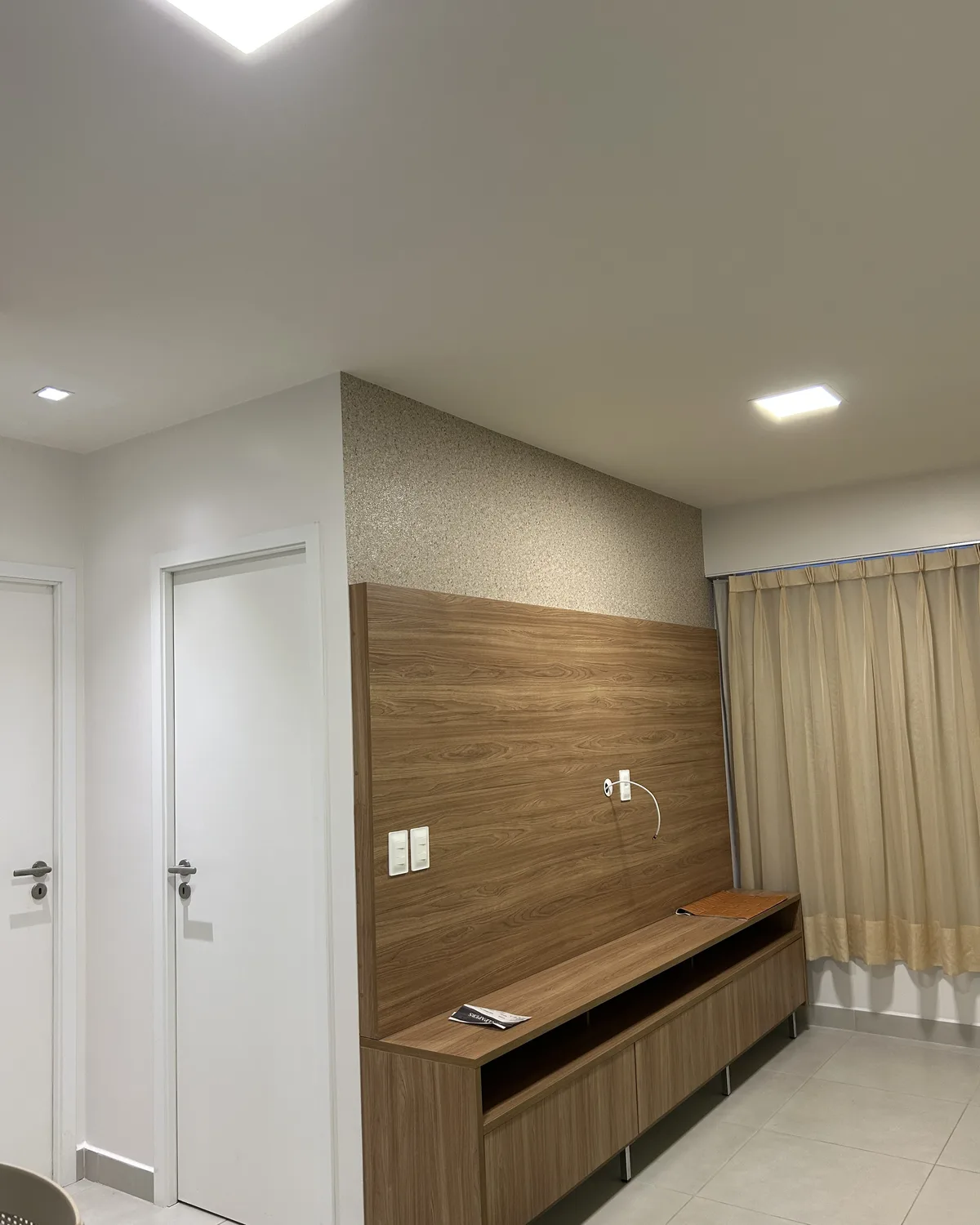 Parede de sala com papel acima do painel de TV de acabamento amadeirado