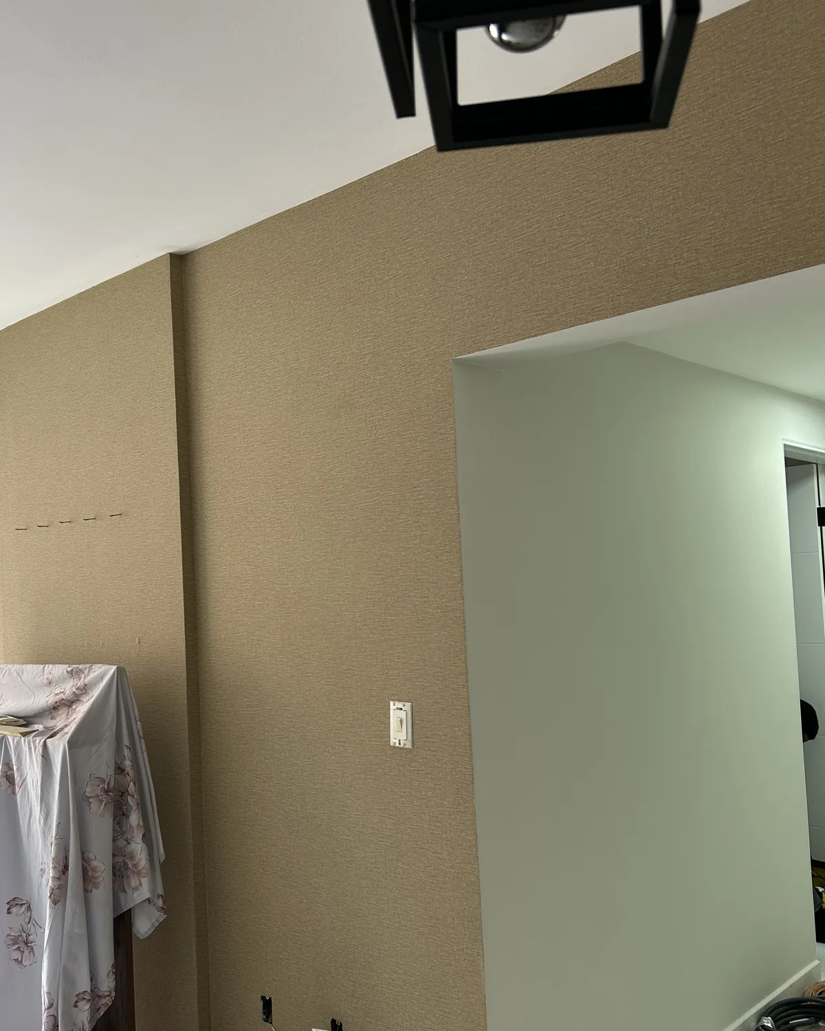 Papel de parede em tom quente aplicado em uma sala, ao lado do vão de passagem