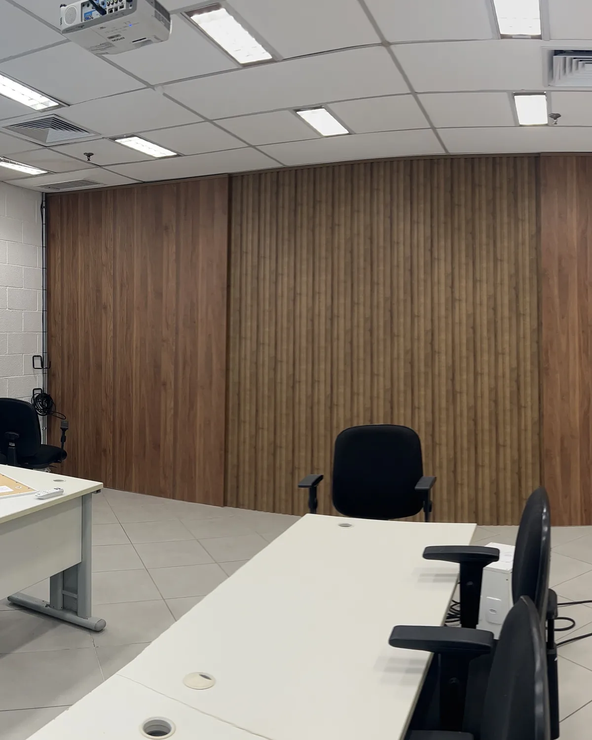 Sala comercial com a parede do fundo revestida em painéis de acabamento amadeirado